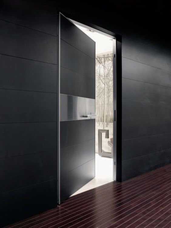 Immagine ingresso casa moderna con dettaglio porta blindata stile minimal moderno, abbinamento laminato nero opaco e striscia in acciaio inox