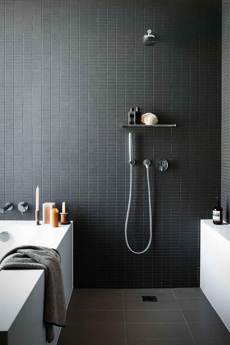 Soluzione per bagno molto piccolo dove vasca e doccia condividano la stessa parete, realizzata in piccole piastrelle nere tipo mosaico.