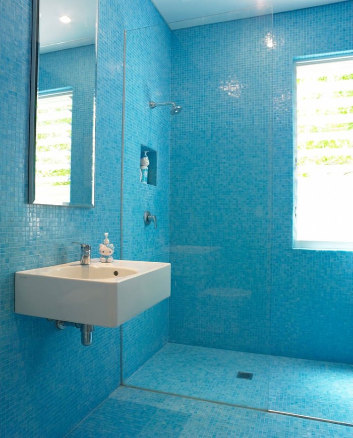 Stanza da bagno per bambini, minimal, rivestito con piastrelle a mosaico blu, con lavabo a parete, doccia a filo pavimento e soffitto bianco