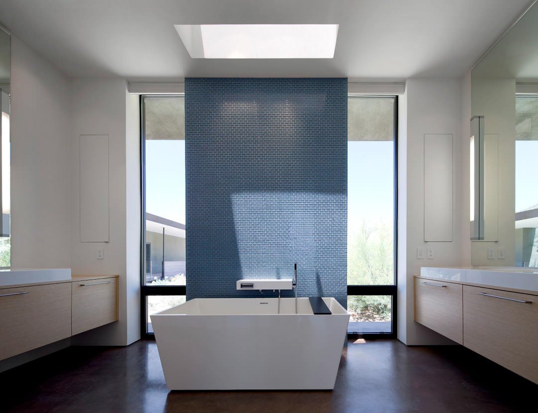 Design di bagno moderno in bianco e blu, molto luminoso, con il colore dei mobili che si abbina molto bene con il pavimento in cemento