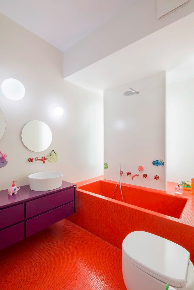 Coloratissimo bagno per bambini con la vasca realizzata in muratura e rivestita in mosaico di colore rosso accesso - il mobile sotto il lavandino colore viola - stile moderno
