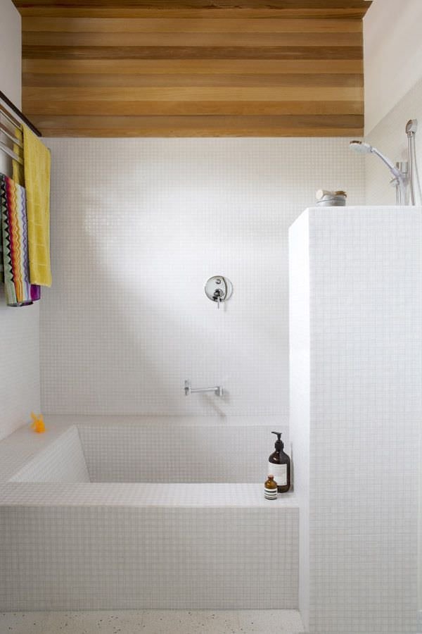 Dettaglio con vasca in muratura rivestita in mosaico bianco - parte del rivestimento e soffitto in legno che aggiunge un tocco di colore e originalità alla stanza