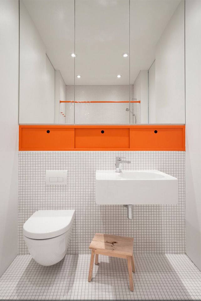 Design piccolo bagno minimal moderno con piastrelle bianche e tocchi di colore arancione. Semplice e particolare
