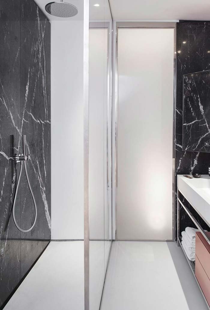 Piccolo bagno moderno con doccia, rivestimenti in grandi lastre di marmo nero, elegante e raffinato. Box doccia in vetro, filo pavimento