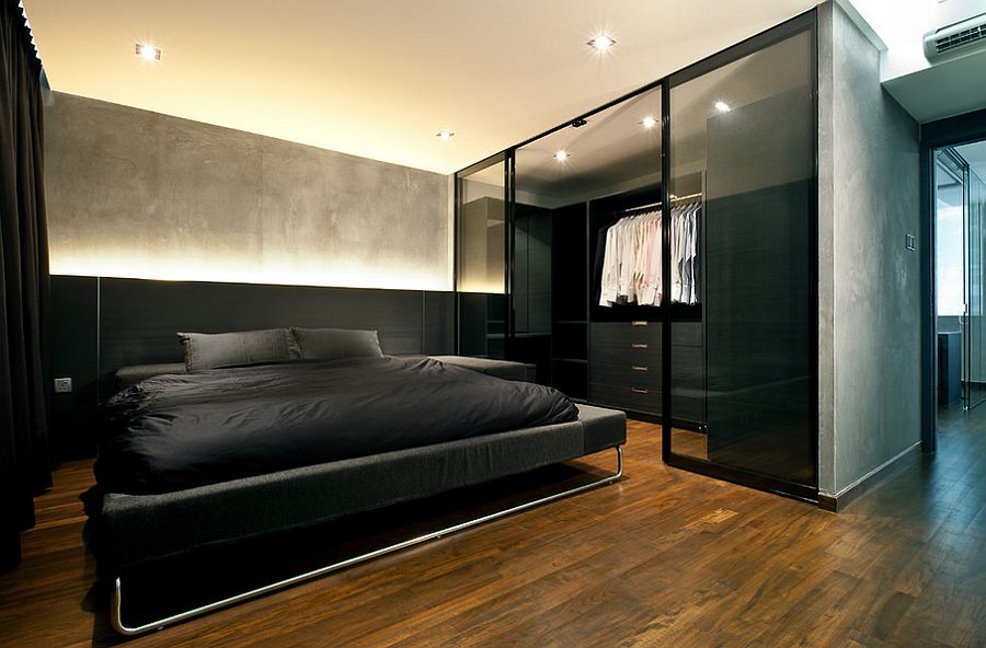 Camera da letto moderna con finiture in legno scuro, parquet spazzolato, contrasti puri che comunicano virilità e mascolinità. La cabina armadio a giorno con pannelli in vetro rafforza l’idea della trasparenza.