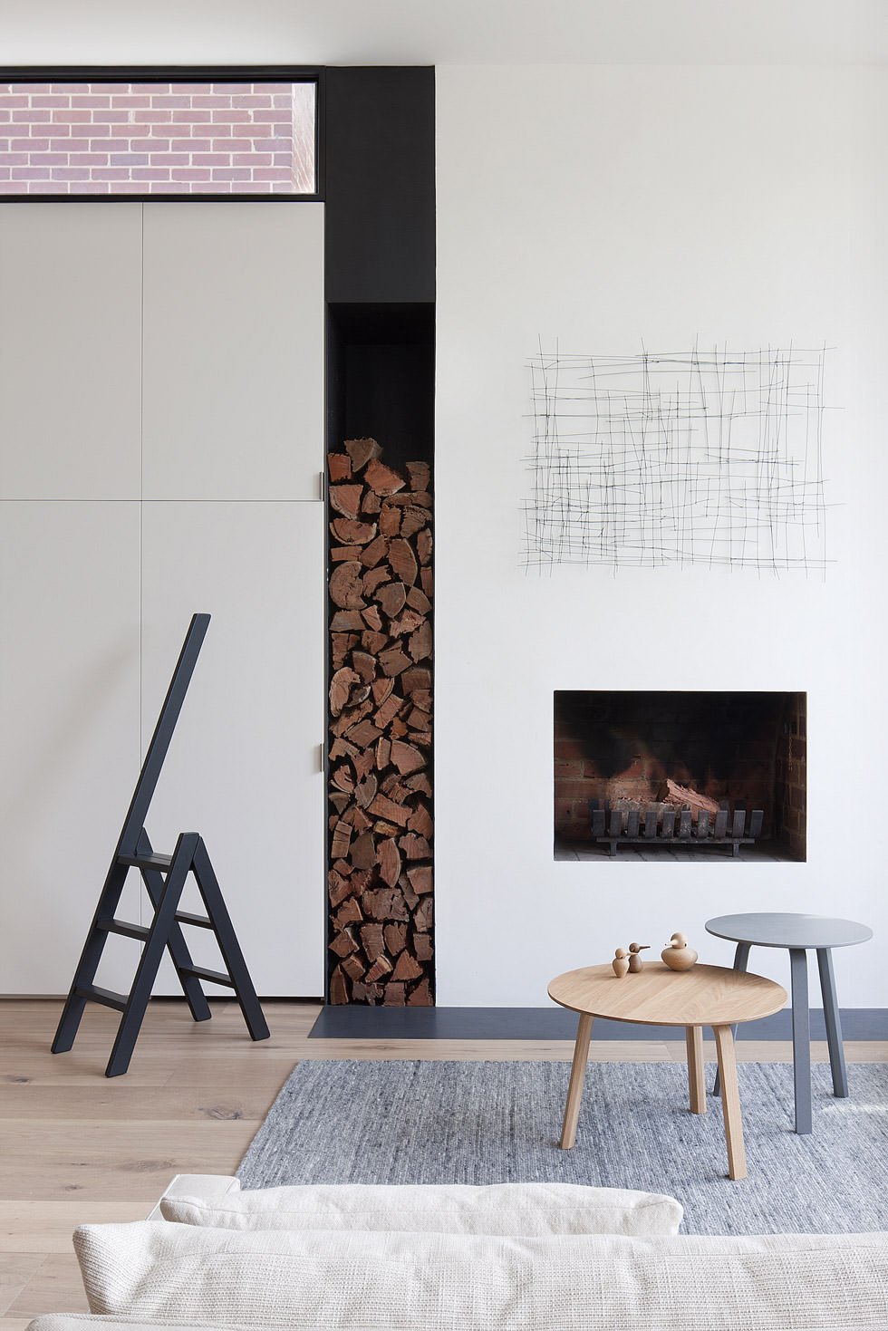 Elegante interno contemporaneo, stile scandinavo, con piccolo camino posizionato accanto agli armadi - bella l'idea per archiviare i tronchi di legno