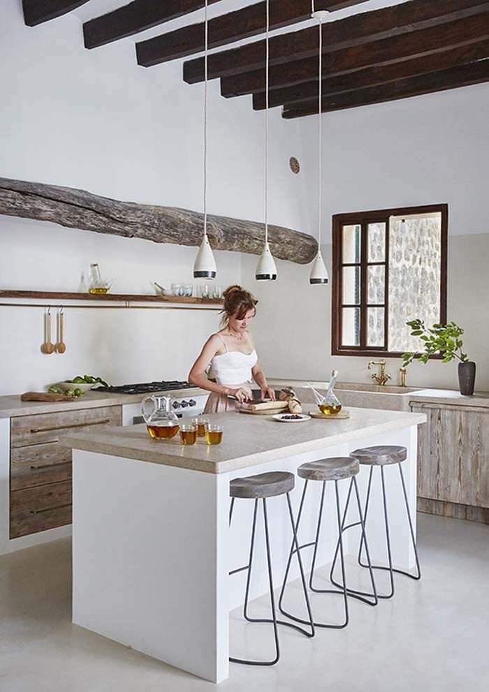 Cucina in muratura dallo stile rustico moderno con top dell'isola in travertino e ante in legno grezzo. Pavimento in cemento e travi a vista in legno scuro.