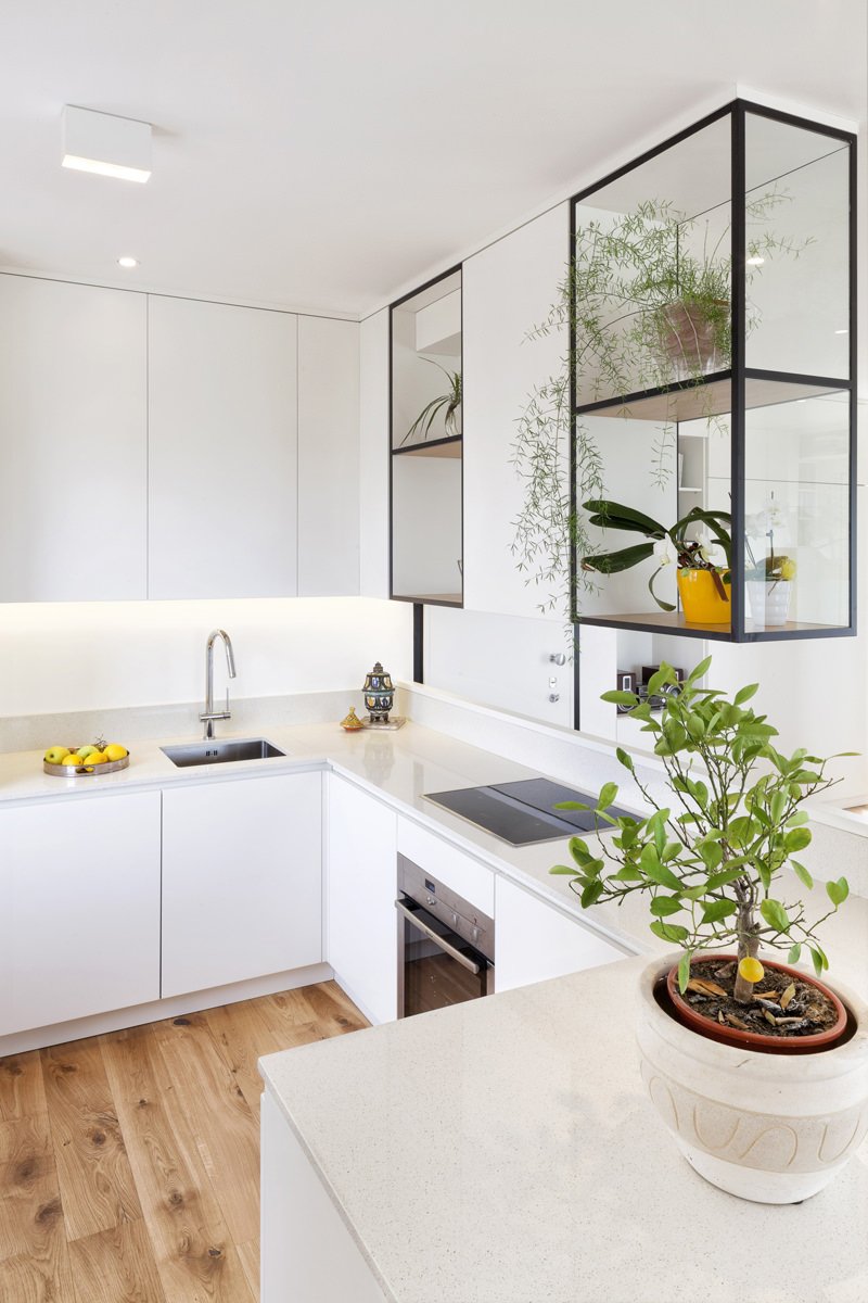 Stupenda cucina moderna bianca con ante in laminato e top in granito ad U. I due moduli sospesi fanno da divisorio con il soggiorno e aggiungono originalità allo spazio. 