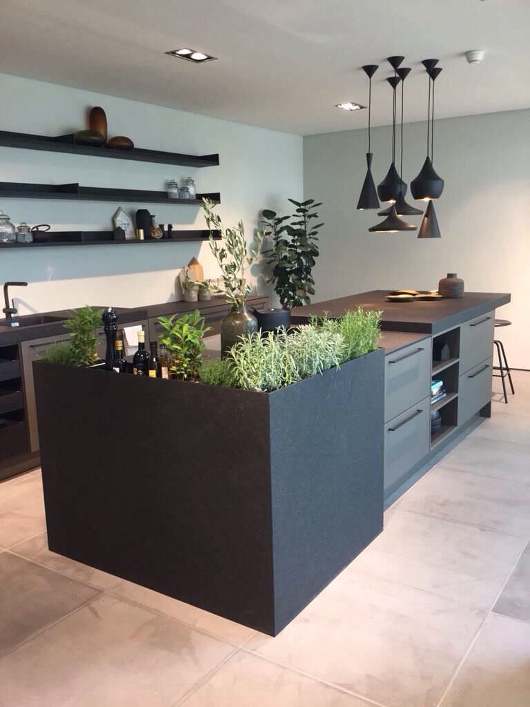 Stupenda cucina moderna nera con pensili a giorno e isola che diventa un grande contenitore per le piante aromatiche. Idea originale e funzionale.