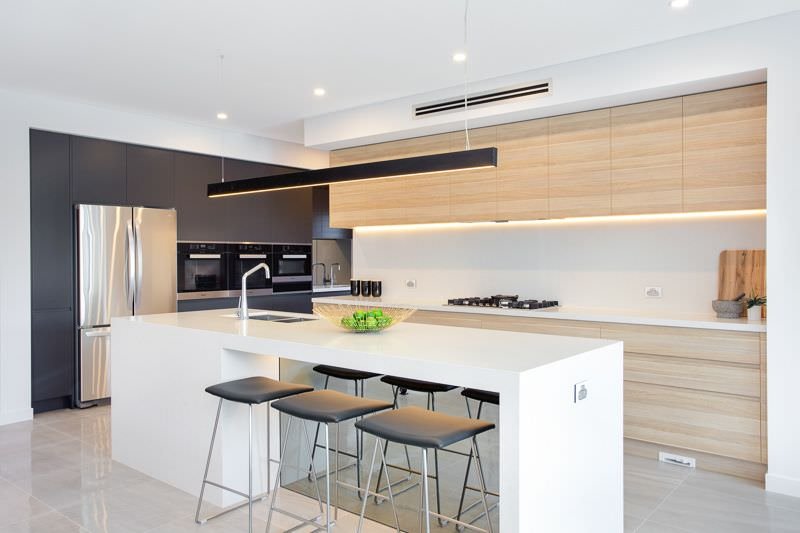 Cucina moderna con isola in bianco, nero e legno in perfetto equilibrio. Pavimenti in marmo. Bella l'idea della illuminazione a led sotto i pensili
