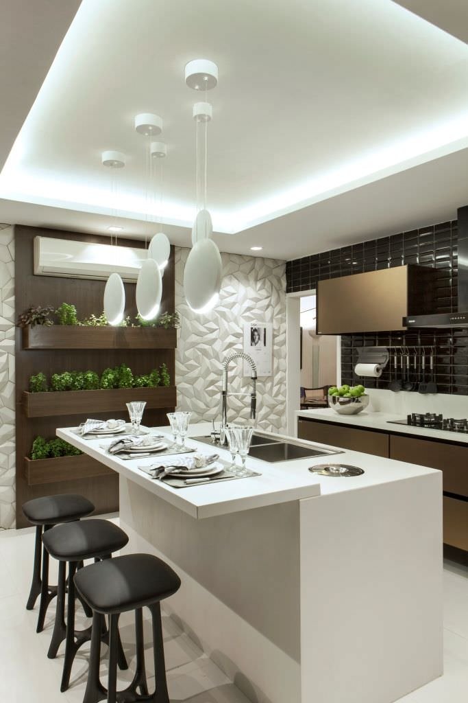 Elegante cucina moderna con isola in laminato bianco ed uno spazio green che ospita piante aromatiche per cucinare. Soffitto in cartongesso con strisce led di luce diffusa. Idee cucine dal design moderno.