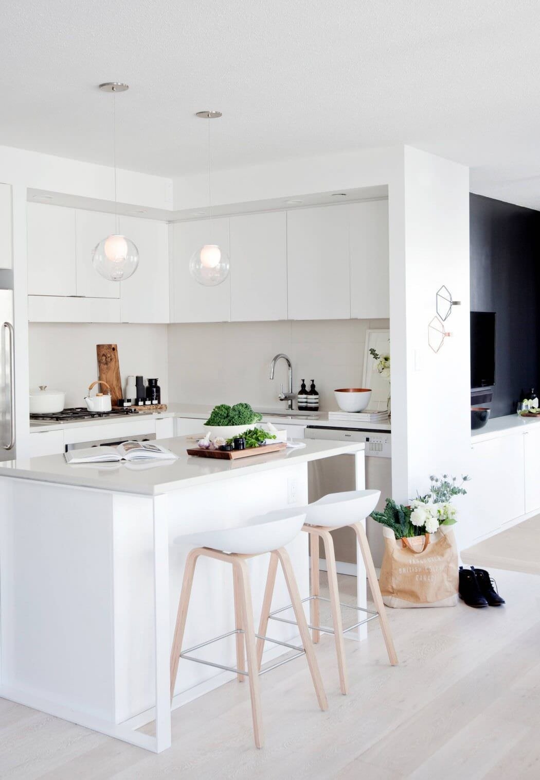 Cucina piccola angolare, stile moderno, con mobili in legno laccato bianco. Una piccola isola delimita l’ambito in modo elegante e funzionale. Idee cucine open space.