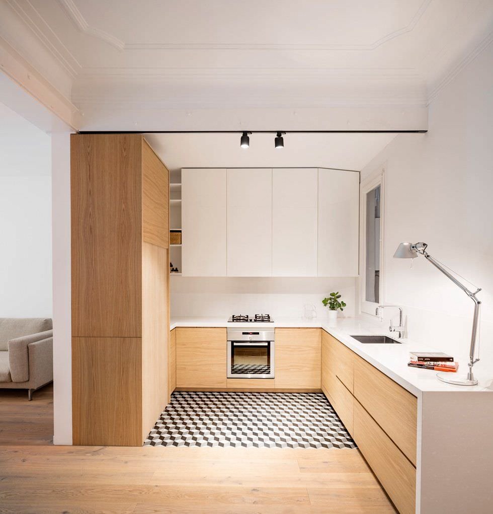 Piccola cucina open space ad U in legno e laminato bianco. Pavimento con piastrelle a motivo geometrico. Idee cucine moderne aperte dal design particolare.