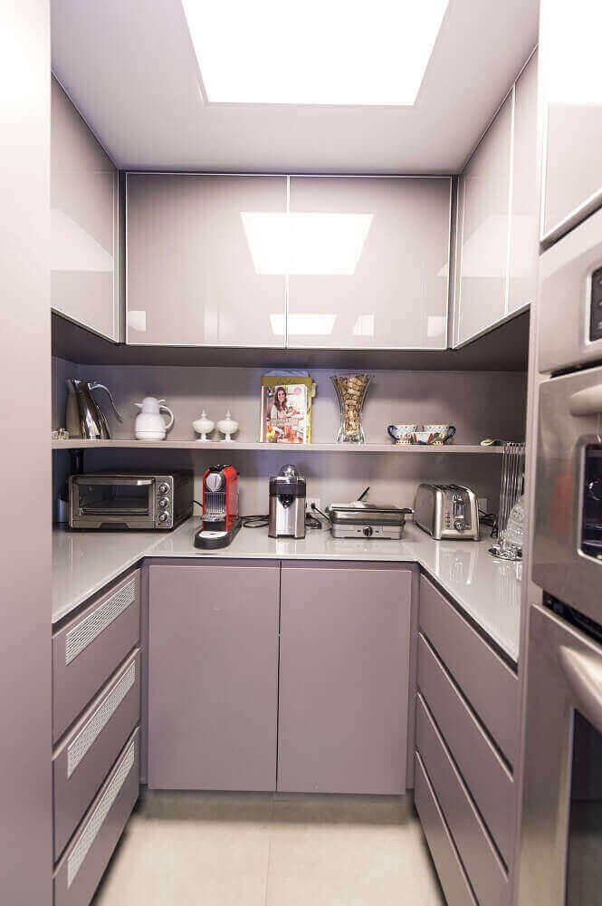 Piccola cucina ad U con i mobili laccati di colore viola chiaro, moderna ed espressiva. Sul soffitto una grande lampada ad incasso per una perfetta illuminazione.