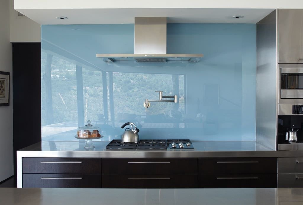 Cucina moderna con rivestimento in vetro, colore blu chiaro - elettrodomestici e top in acciaio e sportelli in legno scuro - rivestimenti moderni per cucine