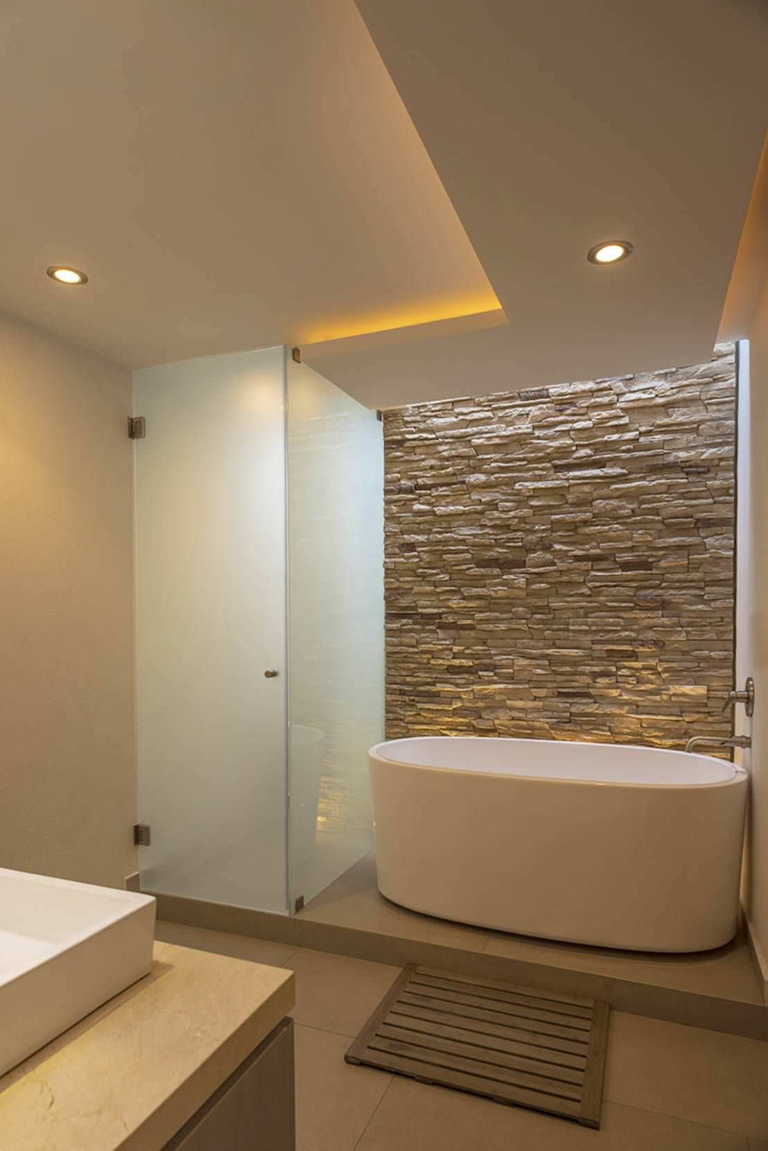 Bagno contemporaneo con vasca e box doccia - rivestimento in pietra - controsoffitti con luce diffusa