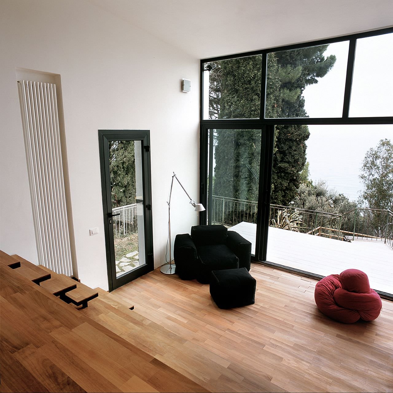 Interno piccolo appartamento - soggiorno vista cucina con una grande vetrata che separa il salotto dalla terrazza, assicurando la visione del mare da ogni punto della casa