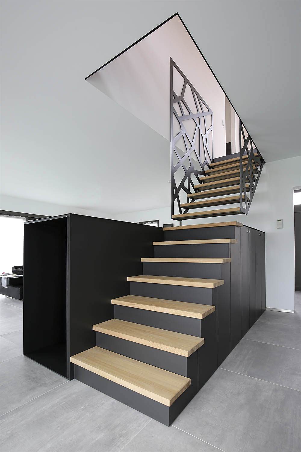 Design scala in legno, stile moderno, realizzata in due pezzi - la parte bassa che si prolunga con un armadio e la parte superiore che si aggancia alla ringhiera del piano superiore