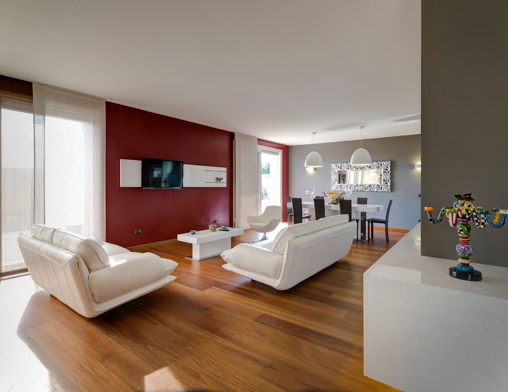 Salotto contemporaneo moderno con le pareti dipinte in rosso porpora e grigio tortora. Divani bianchi e pavimenti in legno - ispirazione colore parete soggiorno